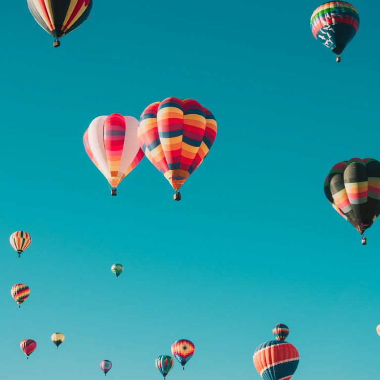 Hot air balloons flying in a blue sky, representing personal growth and therapeutic progress with an accredited therapist.